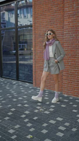 Stylish woman in gray suit with scarf outdoors. Concept of chic urban fashion.