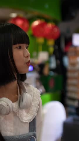A Taiwanese woman in her 20s shops at a souvenir shop at an amusement park in the evening in Shilin District, Taipei City, Taiwan. Slow motion footage.
