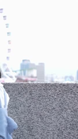 A Taiwanese woman in her 20s walks at an amusement park in Shilin District, Taipei City, Taiwan. Vertical slow motion video.