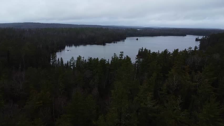 Aerial video of the forests and the amazing lake of Boundary Waters under a dense cloudy sky