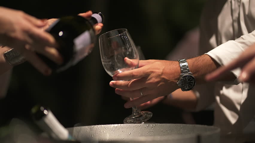 A sommelier serving white wine in slow motion.