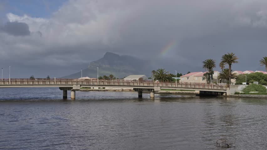 Bridge over Diep River with Table Mountain and a rainbow in cloudy Cape Town, South Africa