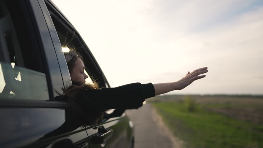 Woman smiles drives with hand in wind person smiles in joy. Feeling breeze woman smiles during scenic drive. Happy drive woman hand catches wind smiling freely on open road. woman smile in wind.