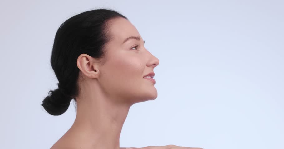 A young Caucasian woman with glowing, flawless skin smiles gracefully in a side profile pose. Perfect for skincare, beauty, wellness, and self-care promotional materials. 