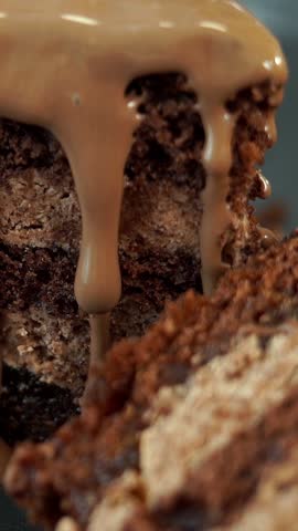 Close up of chocolate cream flows on freshly baked chocolate cake with nut and lemon filling. Food dessert background. Vertical shot