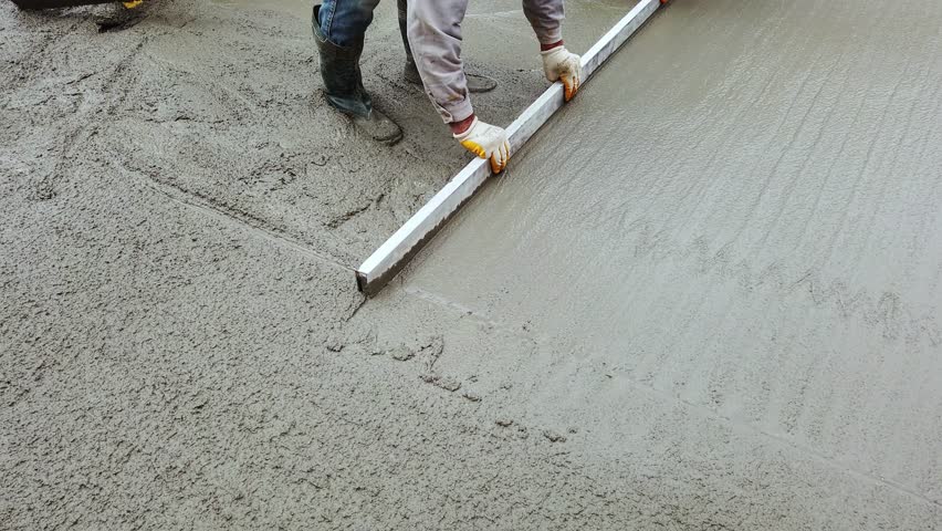 Cast-in-place work using trowels. Worker levels cement mortar. Construction worker uses trowel to level cement mortar screed. Concrete works on construction site