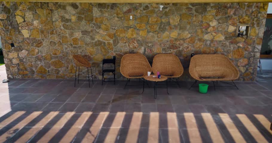 Panoramic shot of an outdoor seating area under a wooden pergola roof, finished with a stone wall in Mexico