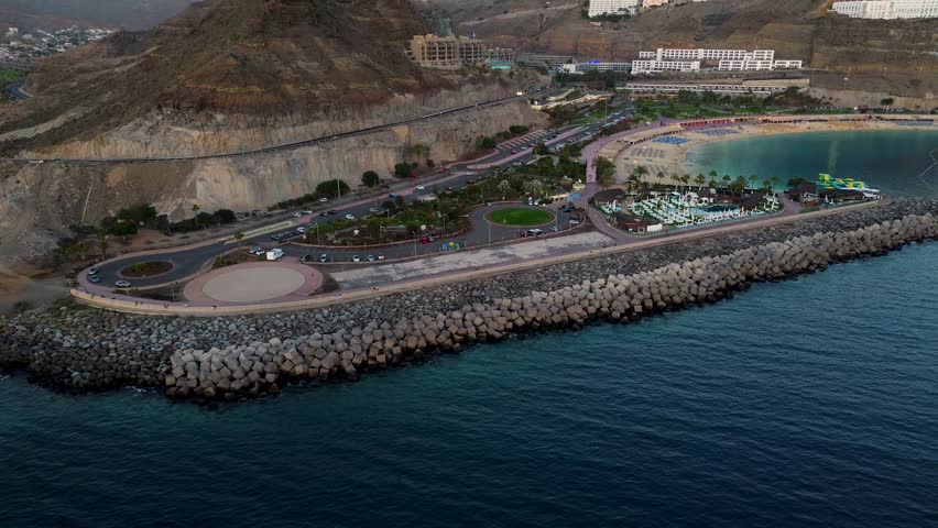 Coastal breakwater ending in a golden sand, calm and crystalline water bay