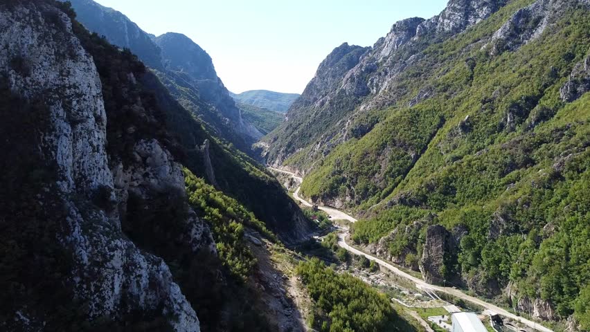 Scenic aerial view in between the mountains of Albania with dirt road going through the valley.