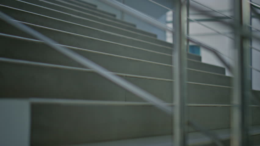 Ambitious manager climbing stairs inside bright modern office back view. Businessman in elegant suit walking upstairs hurrying on work. Confident entrepreneur going up staircase corporate building.