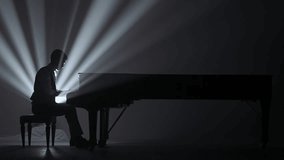 Pianist sitting and playing on the black grand piano on dark concert stage against bright spotlight, isolated on black studio background. Artist performing in concert hall. - Powered by Shutterstock - Get 15% off with code: PIKWIZARD15