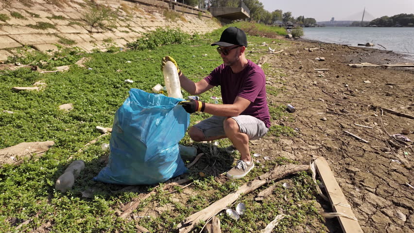 Environmental activist cleaning river shore from piled up trash.	
