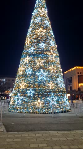 Large Christmas tree with shining lights against the dark sky