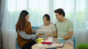 Young asian women giving gifts to friend in pregnant and her husband, pregnant woman unwrapping gift enjoying surprise baby shoes celebrating festive holiday or childbirth party together at home - Powered by Shutterstock - Get 15% off with code: PIKWIZARD15
