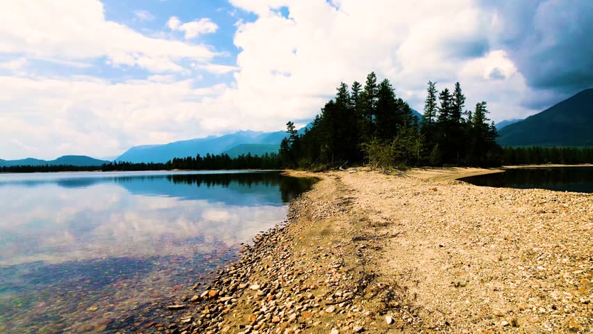 Tranquil lakeshore with forest reflection under blue sky