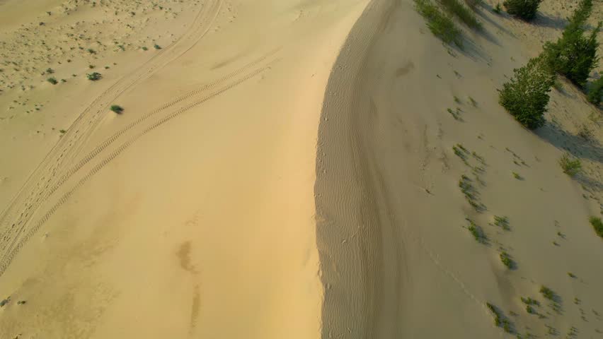 High-speed drone flyover with turns over desert dune and vegetation
