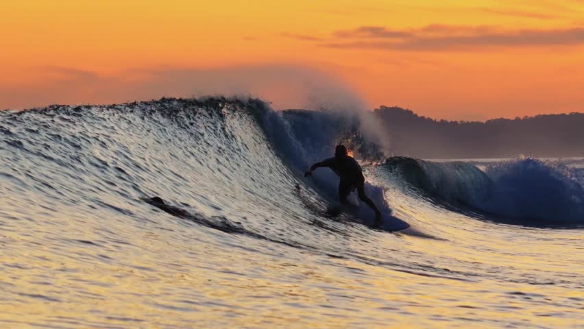 Male surfer on a wave at sunset time at Indian Ocean