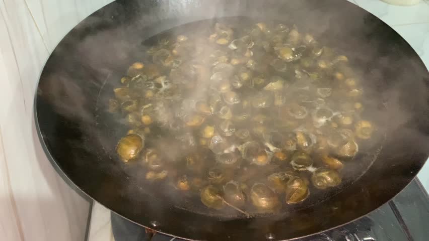 A pan steaming with cooked snails, showcasing a culinary preparation process.