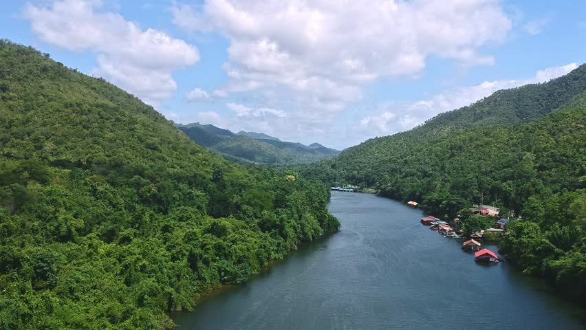 Aerial view of the River Kwai with mountains, forest, and floating houses in Kanchanaburi, Thailand.