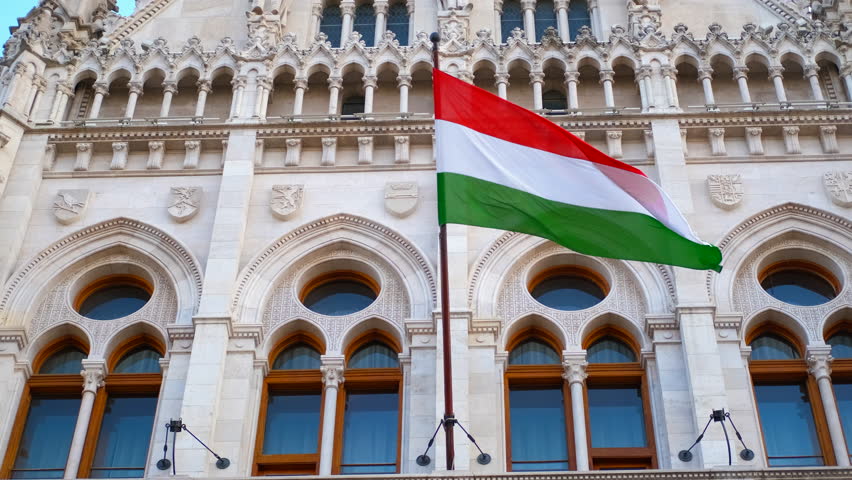 Hungarian flag waving on building. The hungarian flag waves gently in the wind, proudly displayed on the ornate facade of a grand building, showcasing national pride and architectural beauty