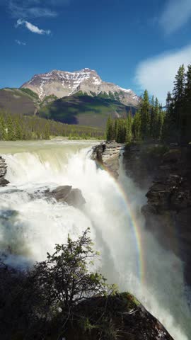 Athabasca Falls with rainbow in Jasper National Park, Alberta, Canada. Canadian Rockies summer landscape. Mount Kerkeslin in the background.