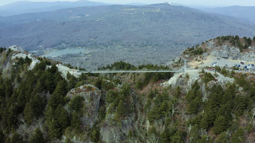 Aerial wide establishing of mile high swinging bridge in Grandfather Mountain in the Appalachians, capturing lush forested ridges and scenic landscapes, static