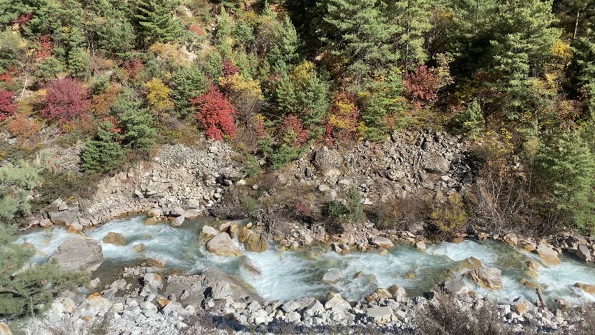 Gushing green waters of the Kali river on the way to Adi Kailash in Uttarakhand, India. Beautiful autumn foliage on the banks