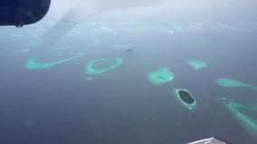 The view from the plane window of the ocean and the atoll. The silver wing of an airplane. There are clouds in places. Turquoise water and snow-white beaches of islands. The Indian Ocean and Maldives - Powered by Shutterstock - Get 15% off with code: PIKWIZARD15