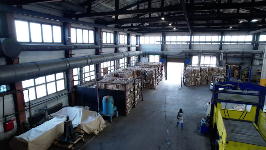 Large preparatory warehouse containing stacks of waste paper bales. Factory hall stores raw materials for creation of finished cardboard boxes