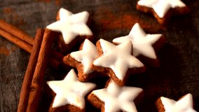 Close-up of a hand with polished nails picking a Christmas star cookie with white icing. The cookies are arranged alongside cinnamon sticks on a rustic wooden table, highlighting festive holiday vibe. - Powered by Shutterstock - Get 15% off with code: PIKWIZARD15