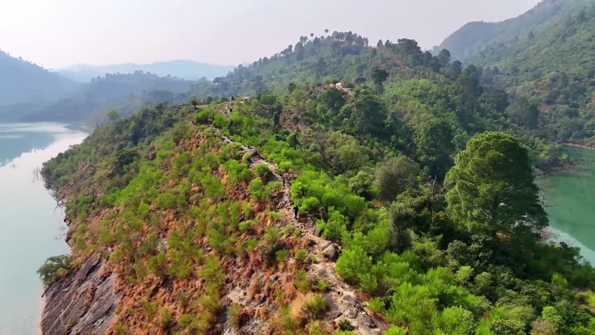 "Beautiful video of a pathway between two lakes on a scenic mountain, surrounded by lush green trees. Perfect for nature, travel, and landscape projects showcasing serene and picturesque beauty."