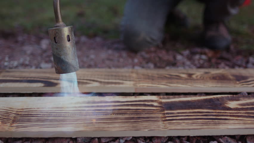 Closeup of blow torch preserving and bringing out wood grain of planks, Yakisugi