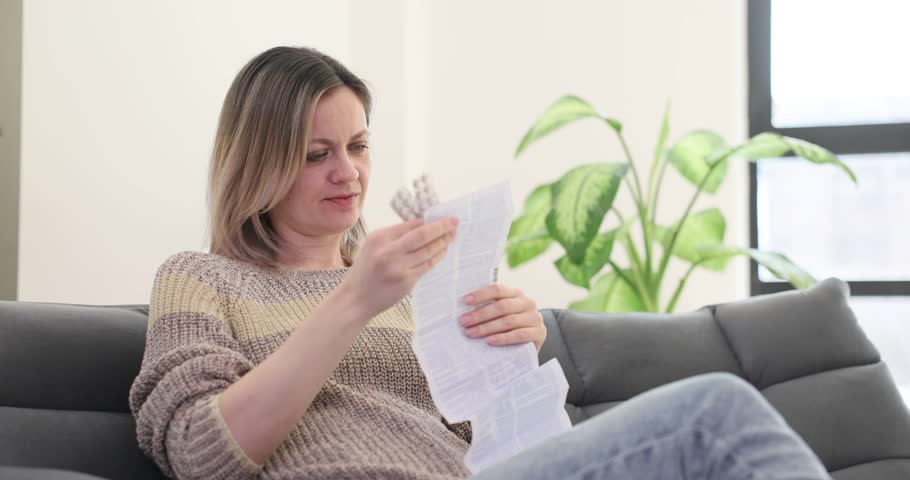 Woman frowns reading medical instructions in living room. Blonde lady expresses concern reviewing warnings mentioned in prescription