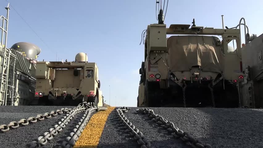 U.S. Marines loading combat vehicles and personnel onto a U.S. Navy landing craft.