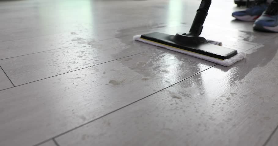 Janitor pushes hot wet mop cleaning laminate in apartment. Worker removes dirt and dust from floor with modern household equipment