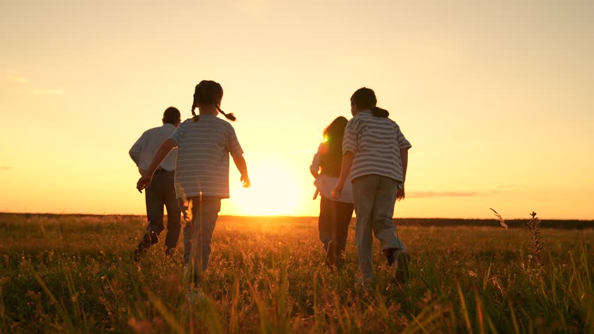 Family mom dad kids play together on weekend, run sunset meadow. Parents boy girl run play together nature. Children parents run in park, friends play in summer. Happy childhood dream. Friends run