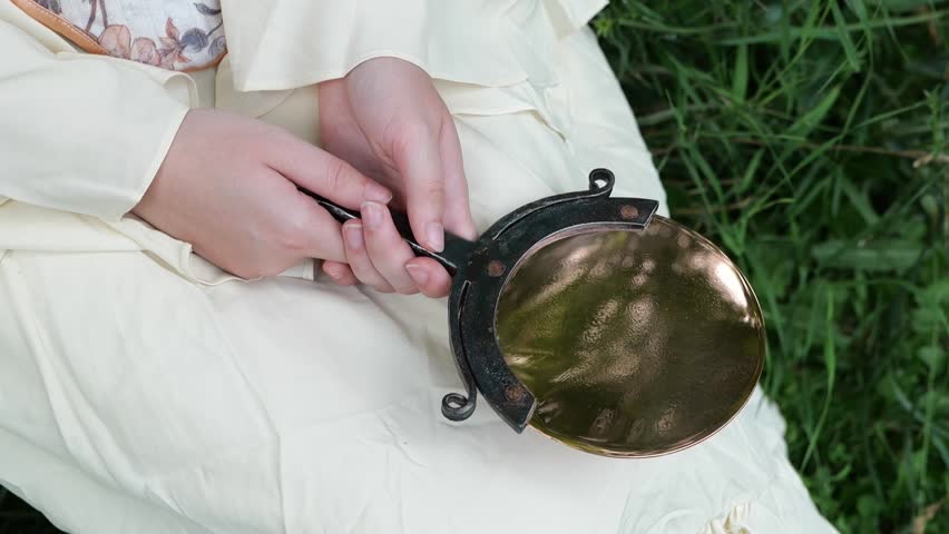 Woman Lifts and Lowers Antique Hand Mirror into Her Lap