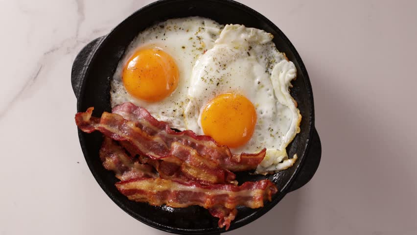 breakfast roasted bacon and eggs on pan top view food rotation