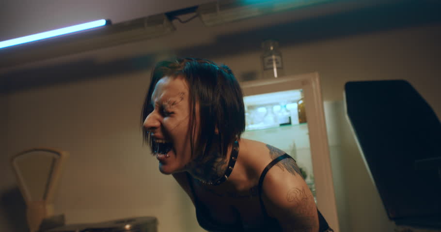 Crazy woman shouting in mental clinic, narcotic withdrawal, tattooed lady. Portrait of emotional drug addicted female person, screaming loudly in rehab, expression of feelings and stress release