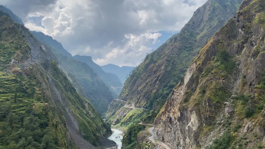 Kali river flowing through valley with a narrow road besides it and surrounded by tall himalayan mountains in Uttarakhand, India