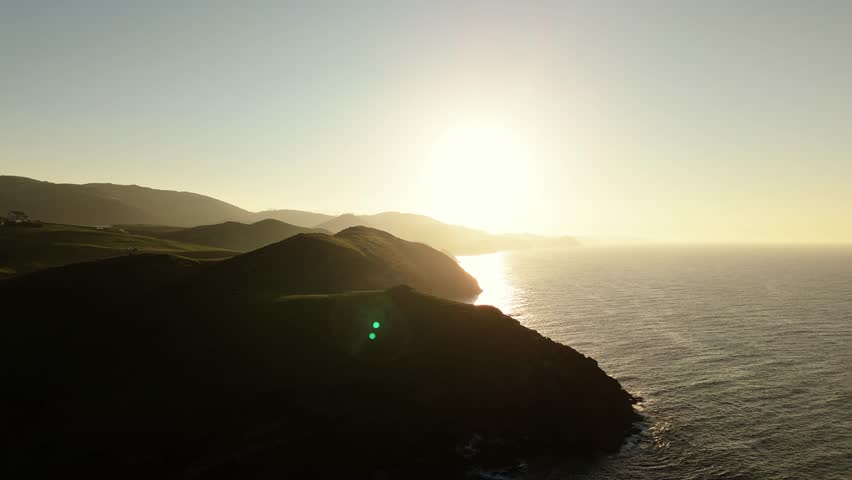 Silhouette of rocky coastline in Spain with bright sunset, aerial view