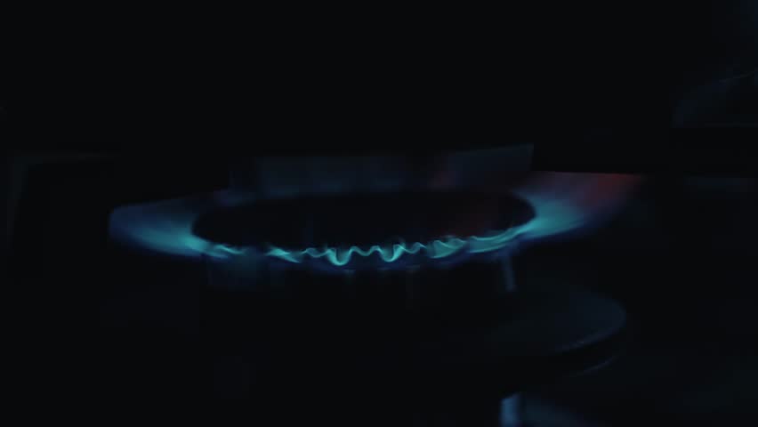 Gas burning from a kitchen gas stove at home. Gas flame with blue reflection.Close-up, selective focus