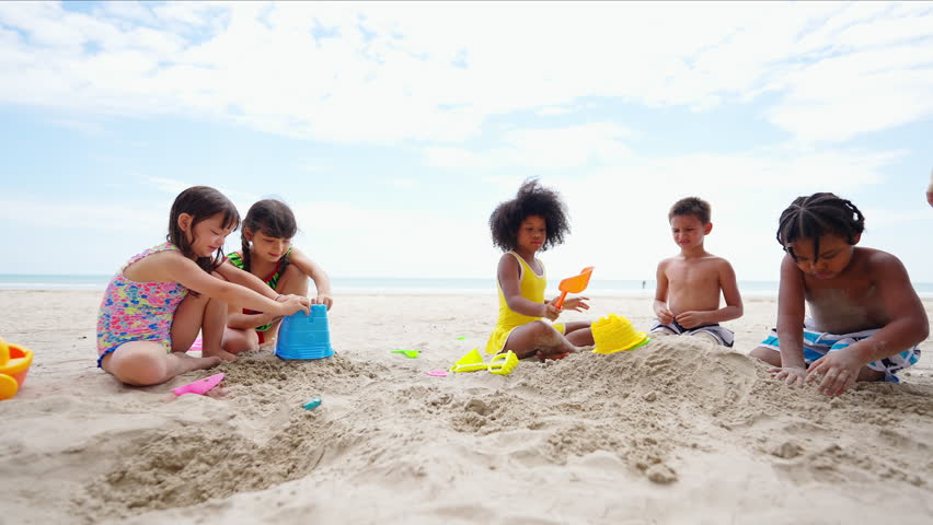Happy Children travel playing at the sea on summer beach holiday vacation. Group of Little cute child boy and girl kids enjoy and fun outdoor lifestyle playing beach toy build sand castle on the beach