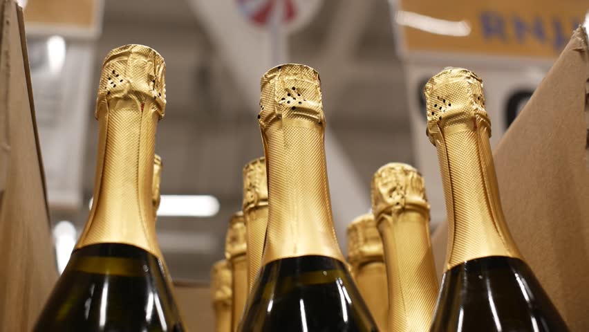 Close-up of a male customers hand taking a golden bottle of champagne or sparkling wine