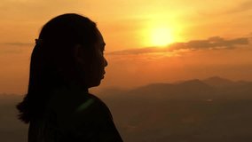 Silhouette of a Christian woman holding a cross praying at sunset. Thoughtful female folding hands into praying gesture. The concept of faith in God - Powered by Shutterstock - Get 15% off with code: PIKWIZARD15