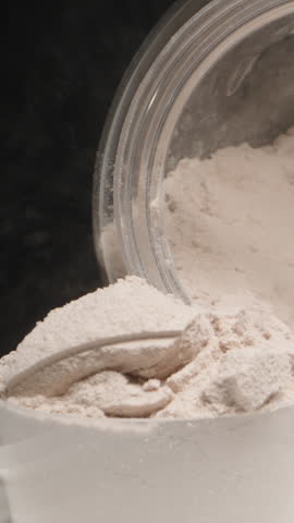 Vertical video. Dolly slider moves in for a close-up as Protein Powder dust disperses into the air. Dolly slider, close up.