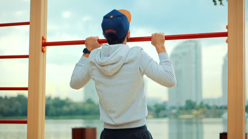 Fitness Sport Street Workout. Muscle Up In Public Gym.Healthy Man On Pull-up Bars Exercising.Chin Ups Burn Fat.Fit Chest Exercise.Athlete Chin Up  Workout Outdoors.Calisthenics Training On Pull Up Bar