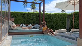Working remotely in a tropical paradise, a freelancer enjoys a serene poolside setting, A diverse couple of man and woman at a pool villa, a freelancer at work by the pool - Powered by Shutterstock - Get 15% off with code: PIKWIZARD15