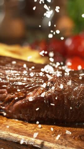 Super Slow Motion of Flying Salt no Raw Beef Steak. Camera Placed on High Speed Cine Bot. Chef is Pouring Salt on the Meal. Filmed on High Speed Cinema Camera, 1000 fps.