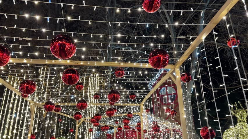 The holiday season in Tbilisi is illuminated with strings of lights and large red baubles hanging over the Christmas market, creating a festive and magical atmosphere.